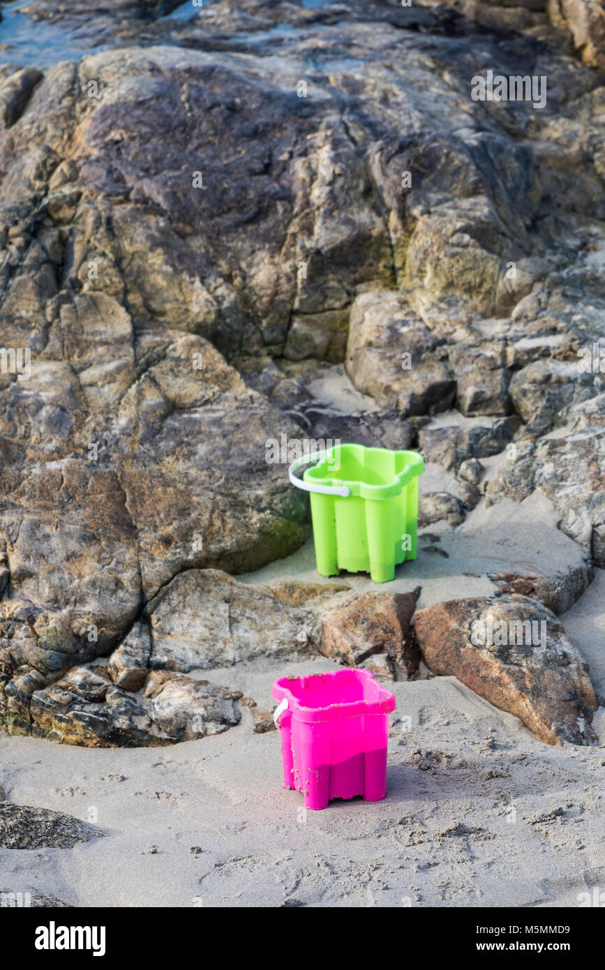 Due coloratissimi secchielli in plastica lasciato sulla spiaggia di Sennen Cove in Cornovaglia. Foto Stock