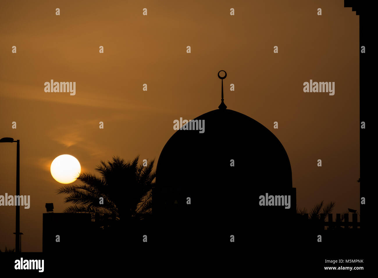 La moschea di cupola della Silhouette contro il cielo arancione al tramonto Foto Stock