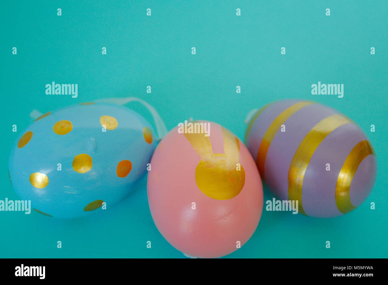 Tre dipinti di uova di Pasqua. Un blu con macchie di oro, rosa con un gold bunny & un viola con strisce di oro. Foto Stock