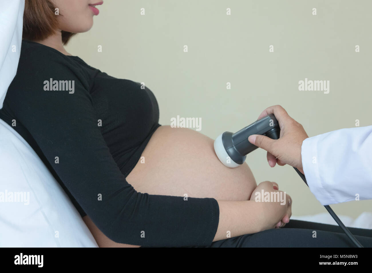 Medico lo spostamento del trasduttore a ultrasuoni sulla donna incinta il ventre Foto Stock