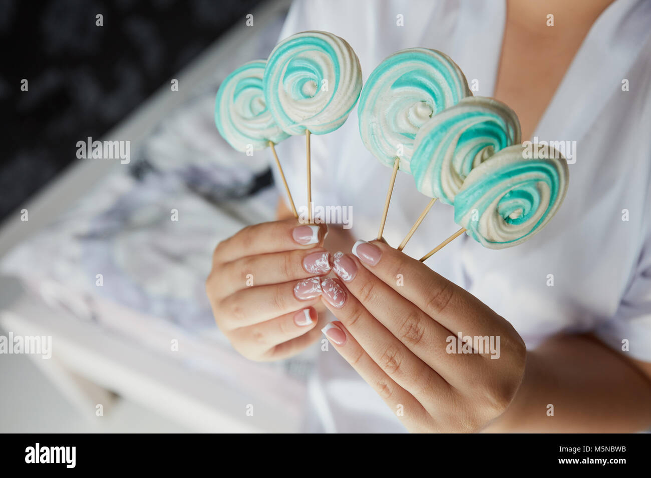 Verde e bianco dolci sul bastone in sposa le mani indossando abito bianco Foto Stock
