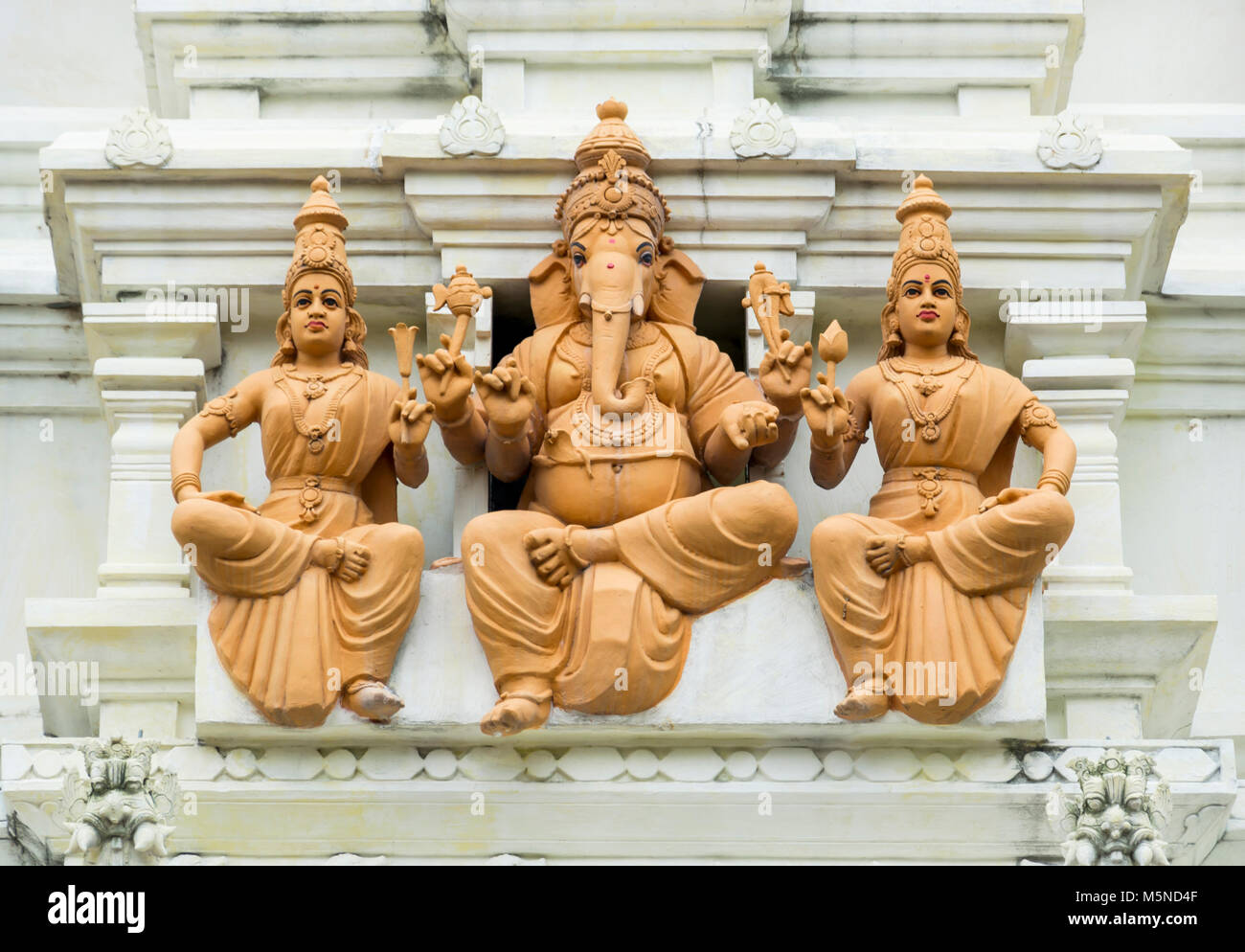 Statua di un dio elefantino Ganesh tra due dee Foto Stock