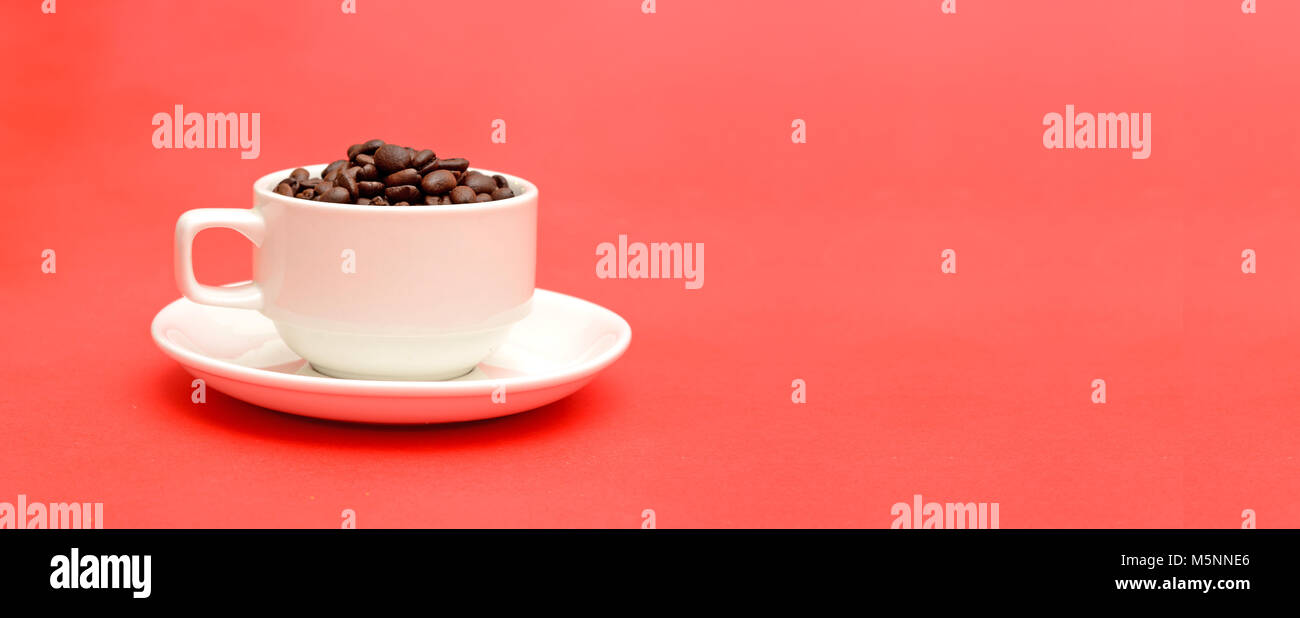 Tazza piena di caffè torrefatto in grani sul banner rosso modello. Foto Stock
