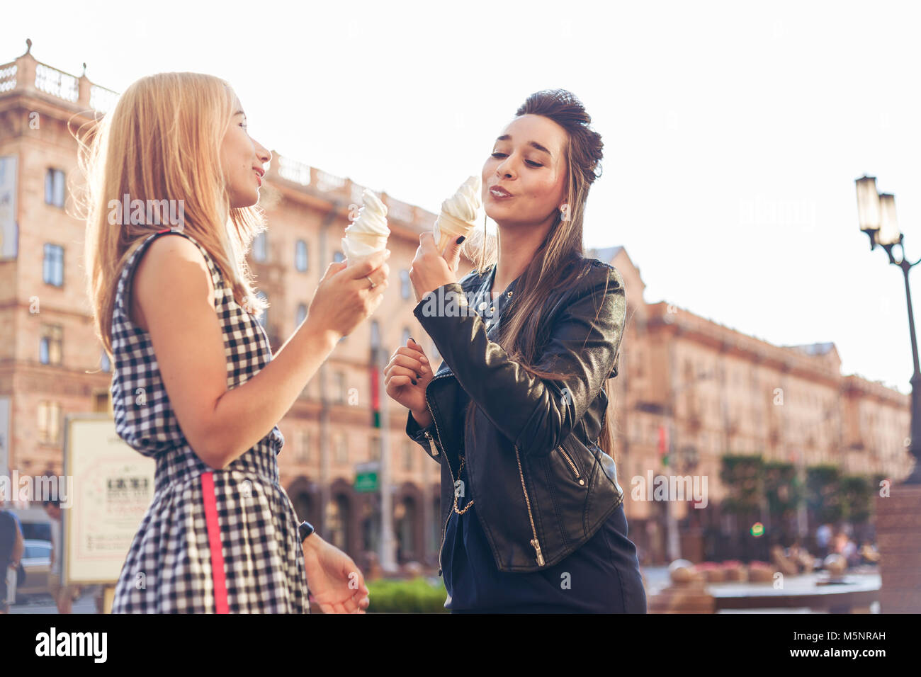 Due migliori amici avente gelato insieme all'esterno. Le giovani donne a mangiare il gelato e ridere. Foto Stock