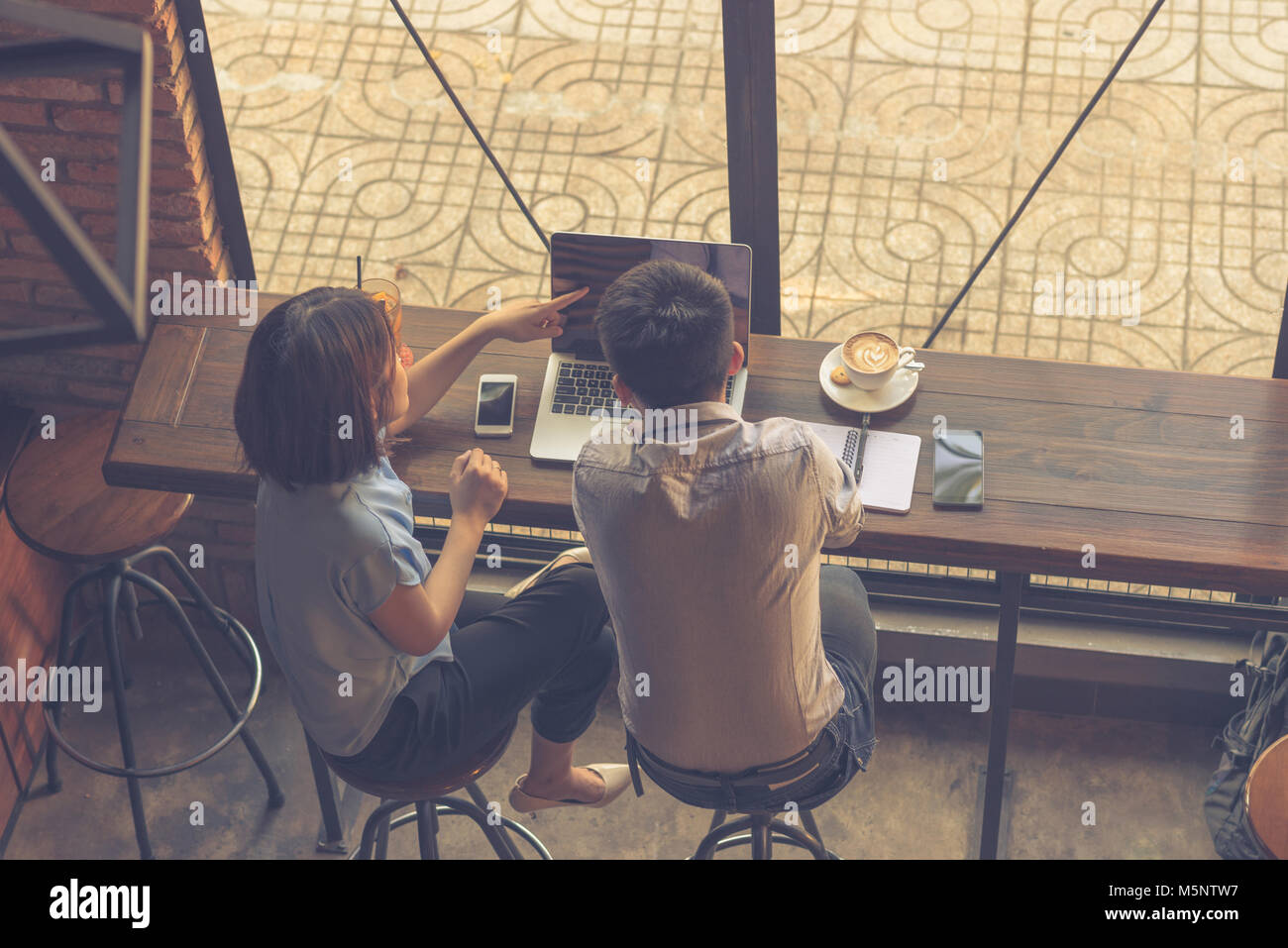 Punto di donna al laptop e discutere con i partner Foto Stock