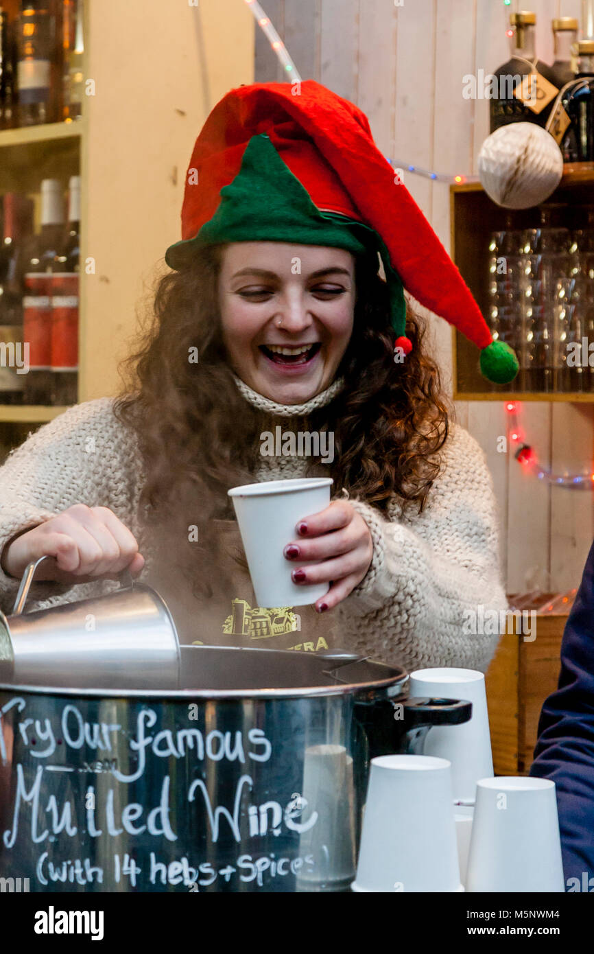 Una giovane donna Vendita di vino brulé in Borough Market al tempo di Natale, London, Regno Unito Foto Stock