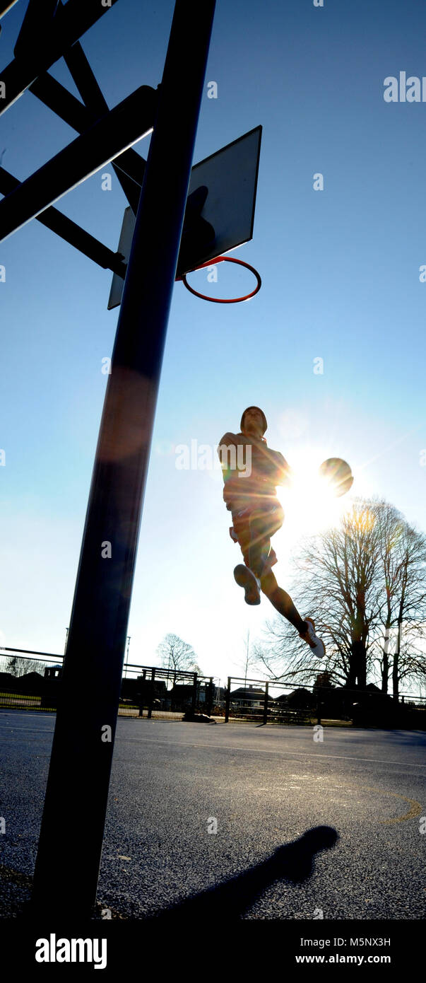 Un esterno di riprese di un giocatore di basket a Devizes, Wiltshire. Girato in luce naturale del sole su un campo da basket. Ampia profondità di archiviato, buona illuminazione. Foto Stock