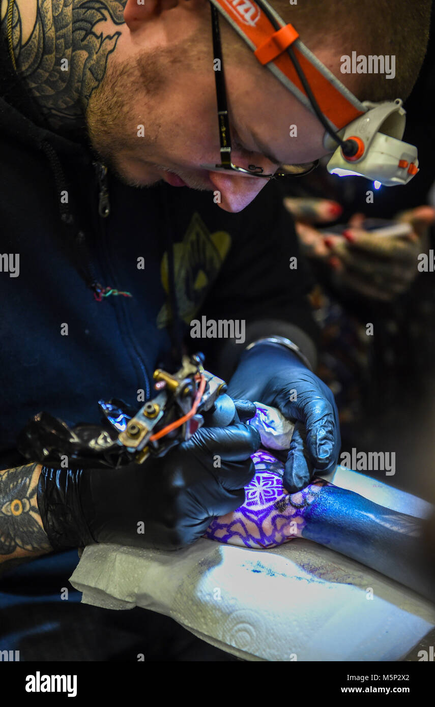 Brighton Regno Unito 25 Febbraio 2018 - Tattooists a lavorare alla undicesima edizione del Brighton Tattoo Convention tenutasi nel centro di Brighton nel corso del fine settimana attirando tattoo artisti provenienti da tutto il mondo Credito: Simon Dack/Alamy Live News Foto Stock