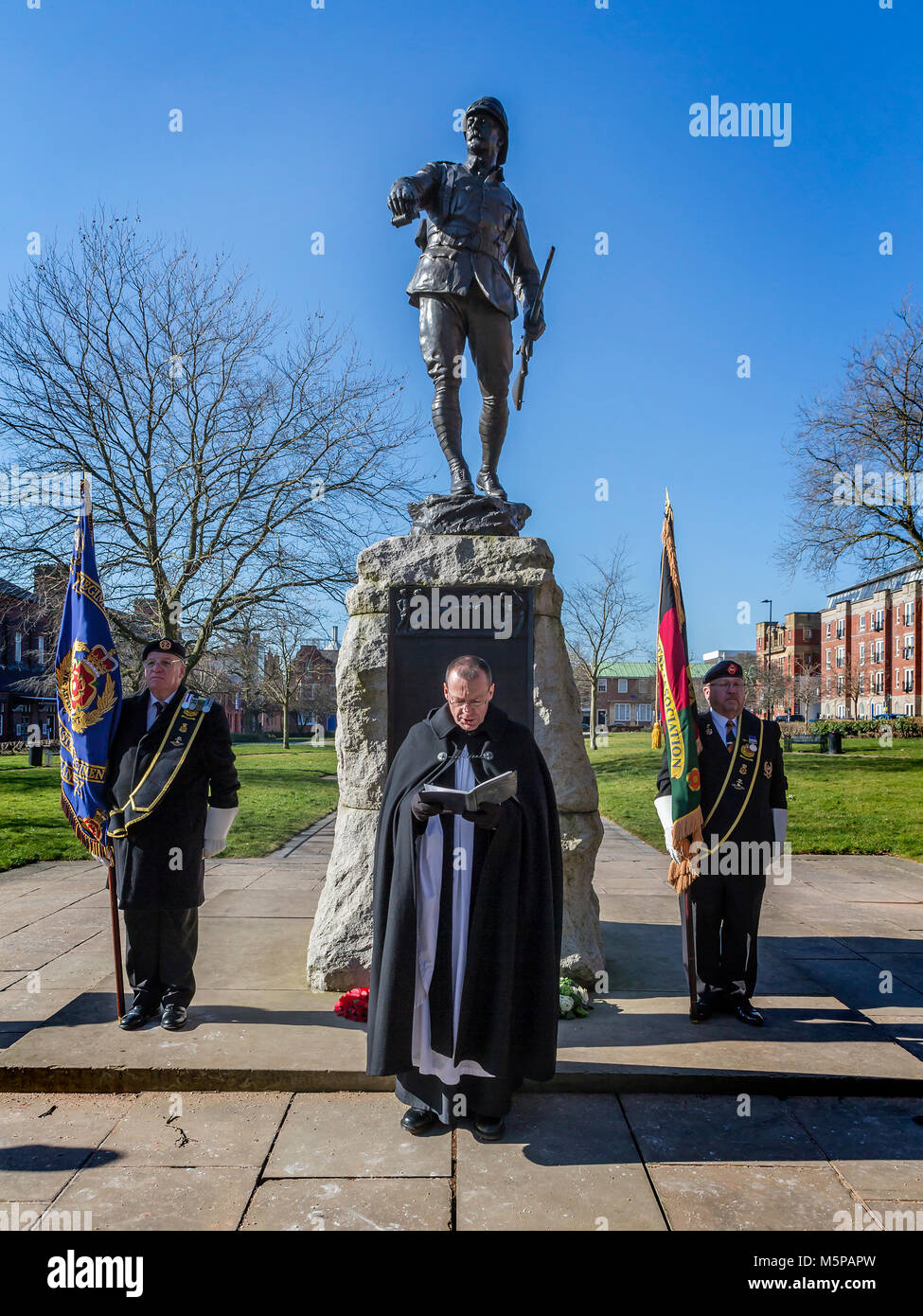 Warrington, Cheshire, Regno Unito. Il 25 febbraio, 2018. Alfieri stand di attenzione come il rettore di Warrington, San Elphin, Revd. Paolo D Wilson dà una benedizione sotto il ritratto in bronzo Statua di Lt Col W McCarthy O'Leary nei giardini della regina, Warrington. Lt Col McCarthy O'Leary del Sud Lancashire reggimento ha portato la carica a Pieter's Hill nella guerra boera. Credito: John Hopkins/Alamy Live News Foto Stock