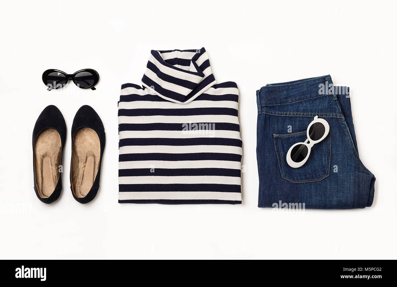 Set di moda di jeans blu, striped maglione, scarpe e sunglsses su sfondo bianco. Messa a fuoco selettiva. Foto Stock