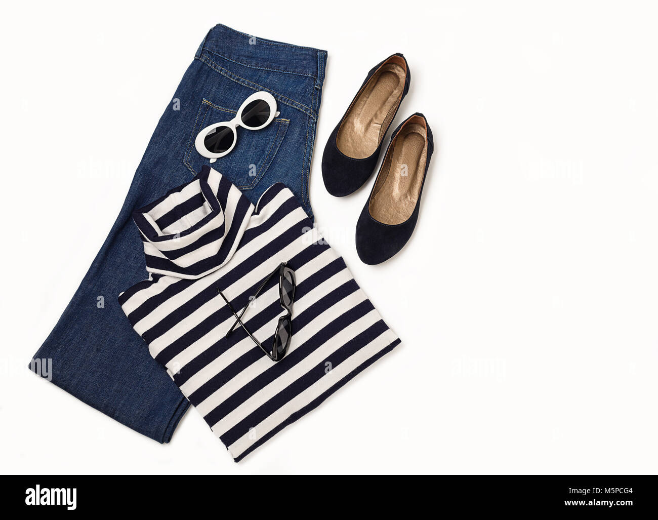 Set di moda di jeans blu, striped maglione, scarpe e sunglsses su sfondo bianco. Messa a fuoco selettiva. Foto Stock