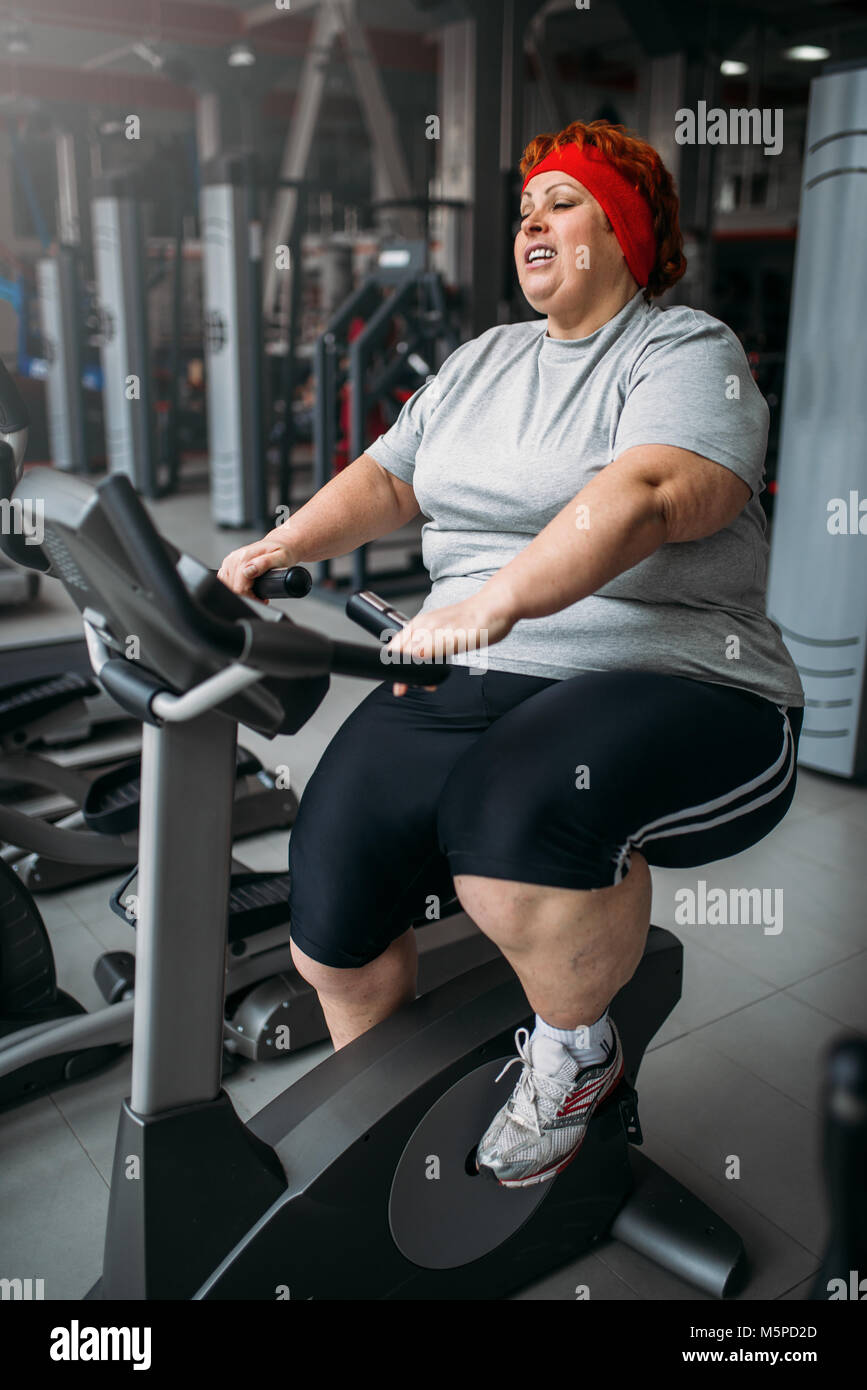 Grasso donna formazione sulla cyclette in palestra. Calorie bruciare, femmina obesi in persona lo sport club Foto Stock