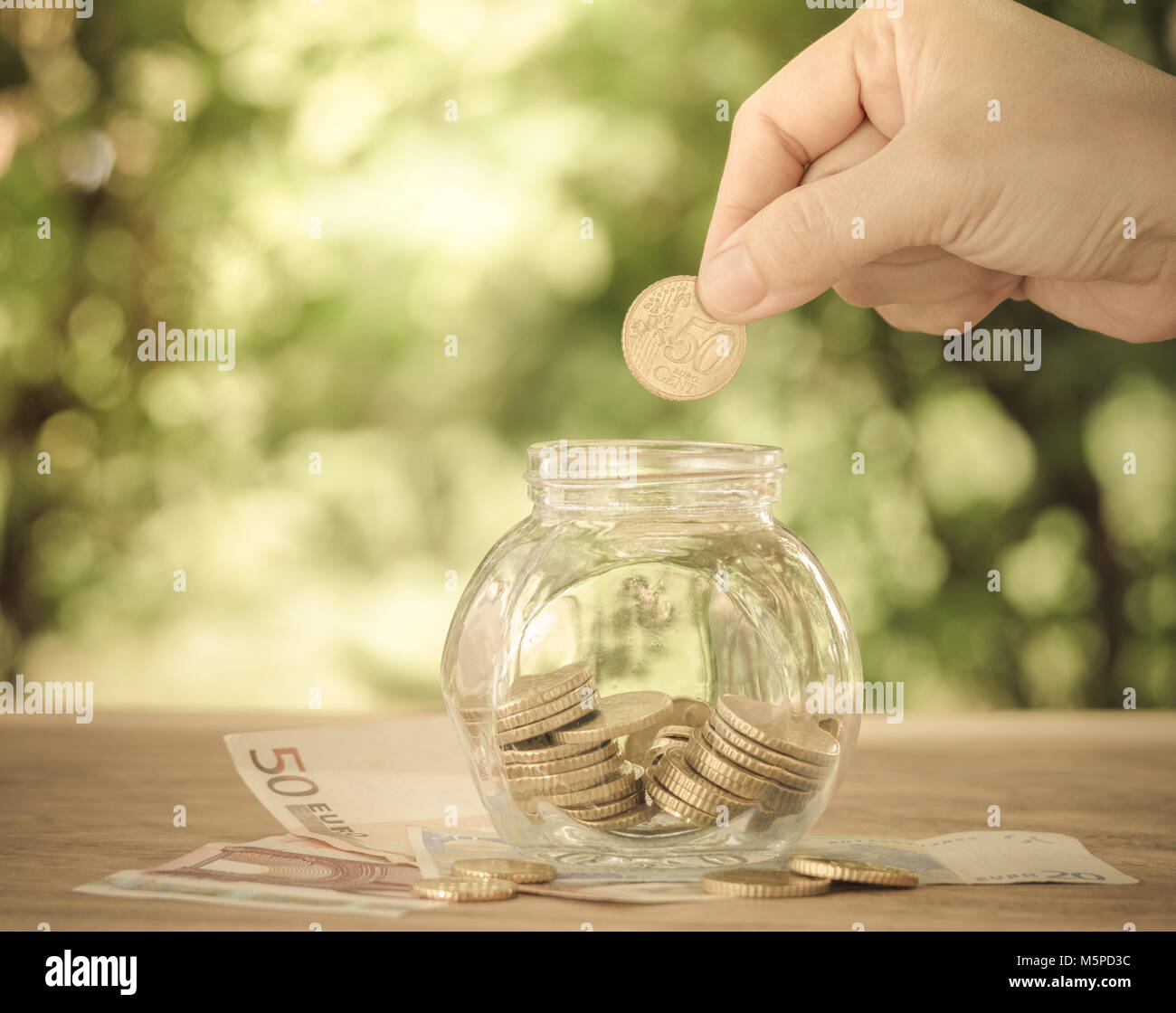 Mano sta mettendo le donne medaglia d'oro in denaro jar. conto concetto,concetto aziendale,finanza concetto. in stile vintage. Foto Stock