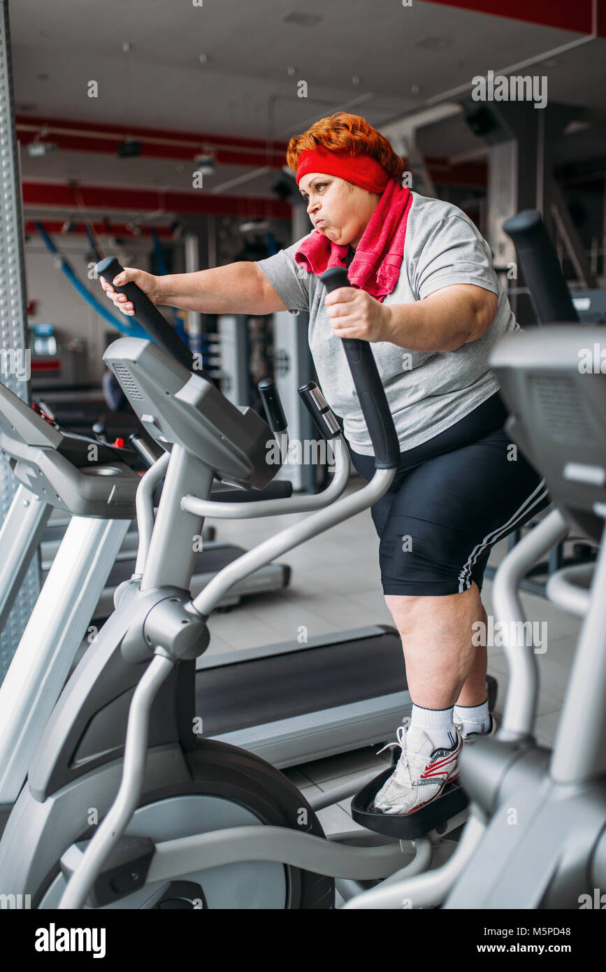 Donna grassa utilizzando l'esercizio macchina per passeggiate, allenamento in palestra. Calorie bruciare, femmina obesi in persona lo sport club, grasso di persone Foto Stock