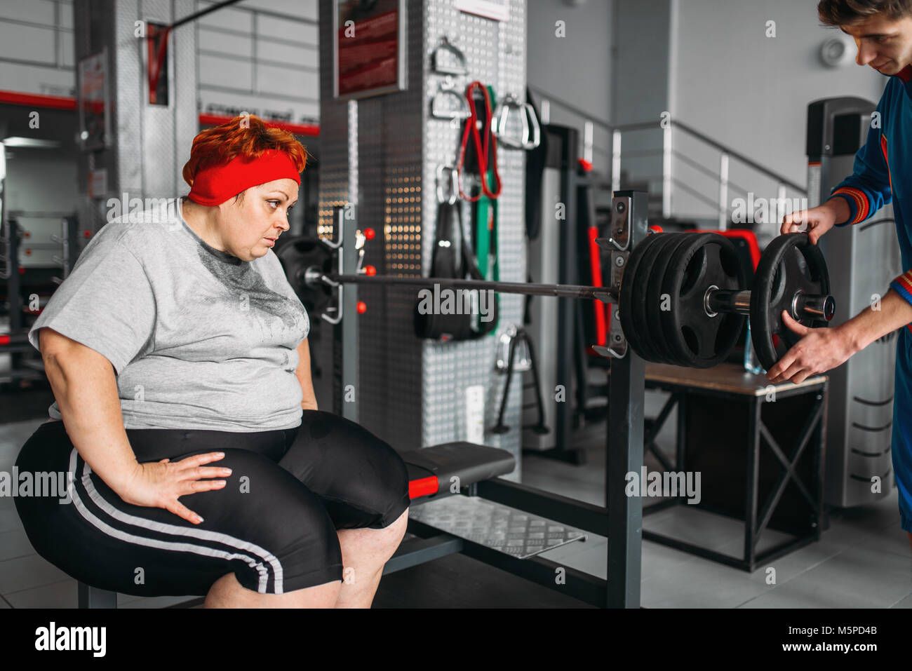Il sovrappeso sudati donna su allenamento con barbell in palestra. Calorie bruciare, femmina obesi in persona lo sport club Foto Stock