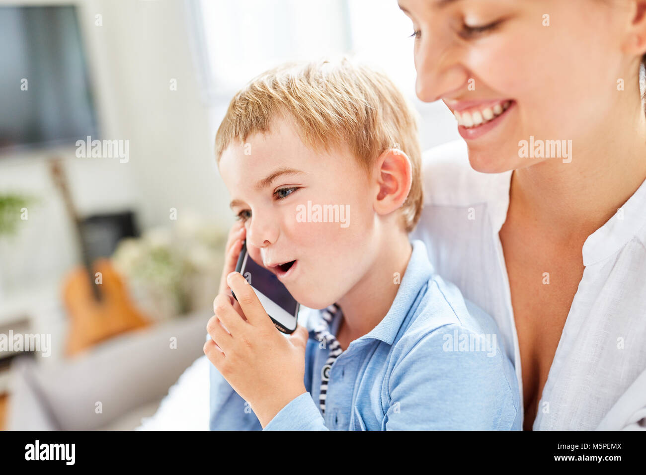 Ragazzo sorridente telefona con lo smartphone sotto la supervisione del servizio di babysitter Foto Stock