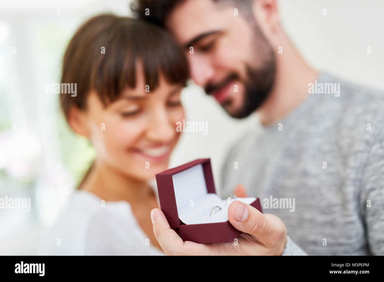 Giovane uomo con gli anelli di nozze in una scatola rende una moglie proposta alla moglie Foto Stock