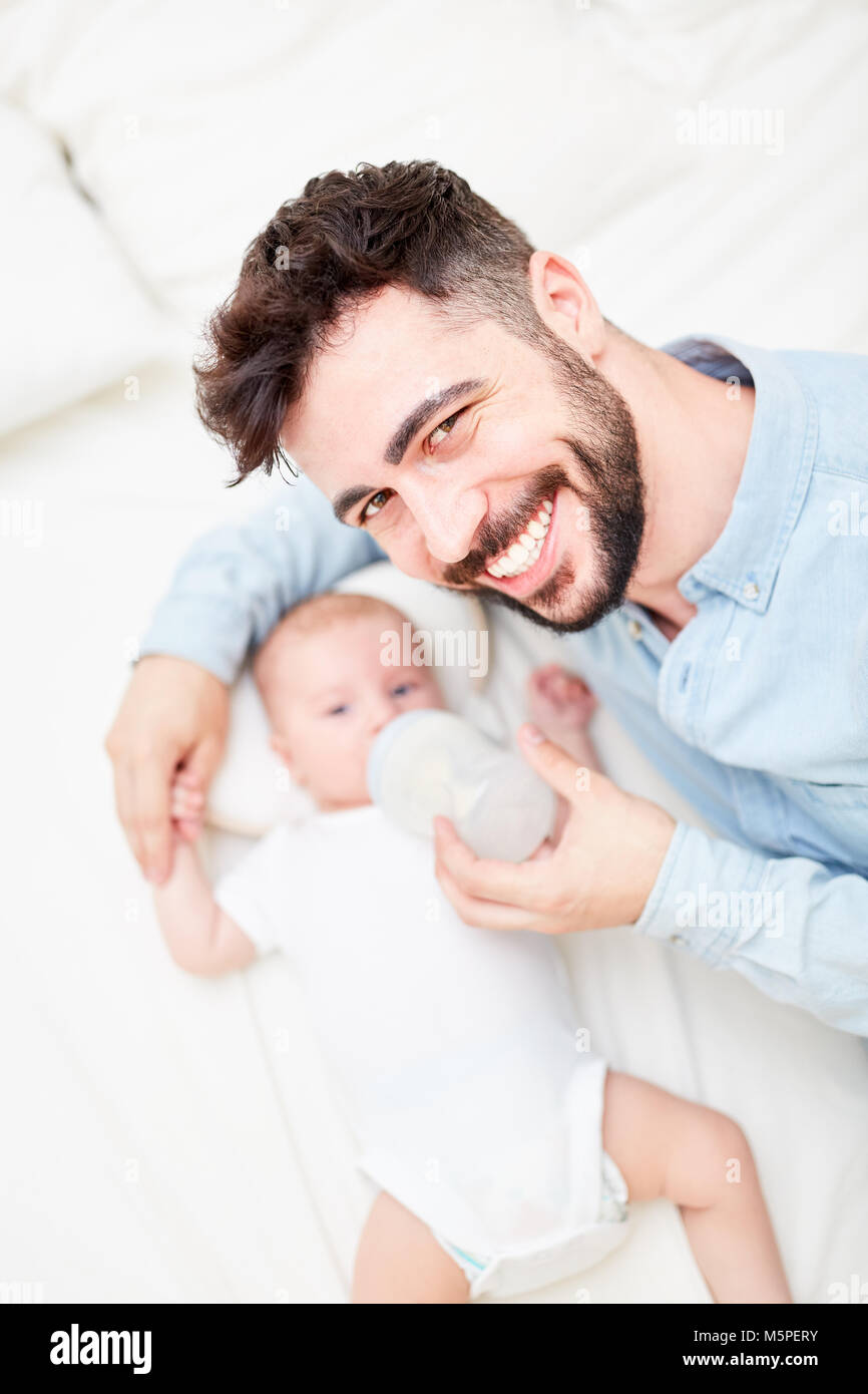 L'uomo come un padre Felice orgogliosamente sorrisi e fornisce baby la bottiglia con il latte Foto Stock