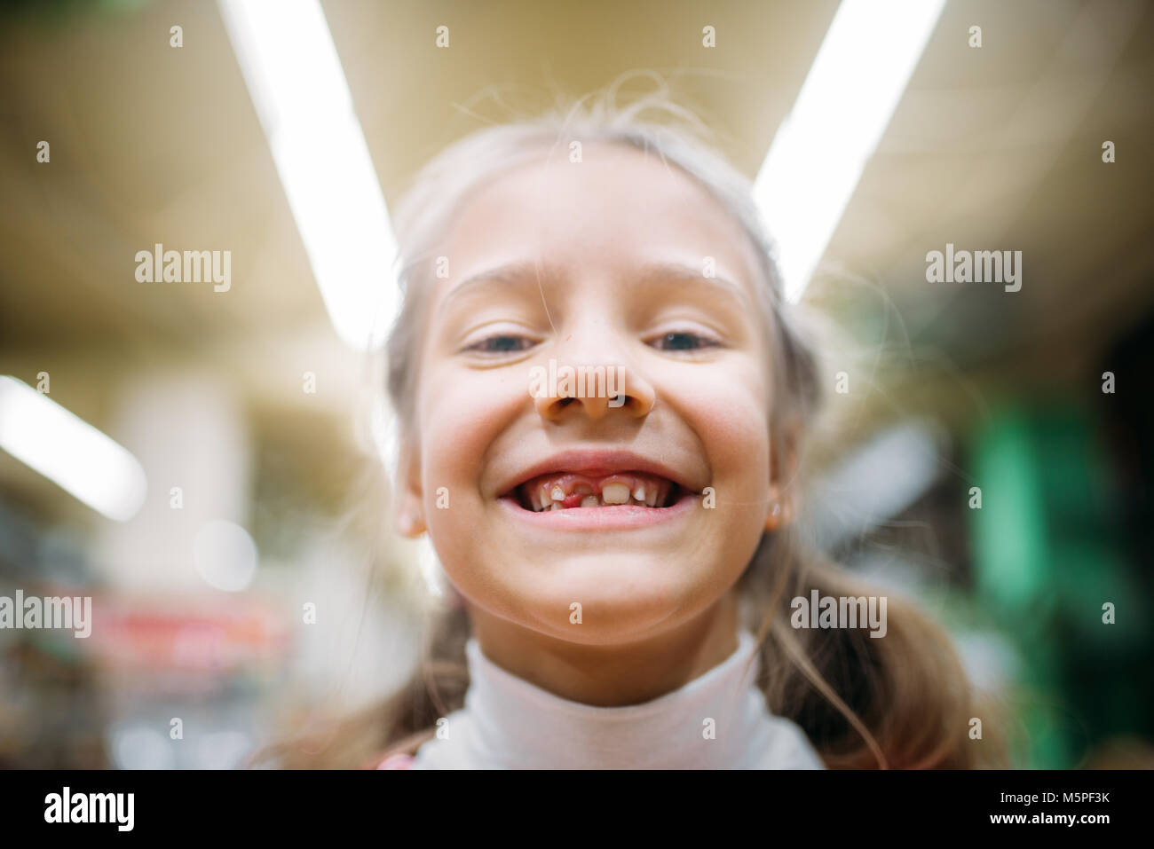 Sorridente bambina senza dente, la felicità dei bambini in pet shop. Kid cliente in petshop Foto Stock