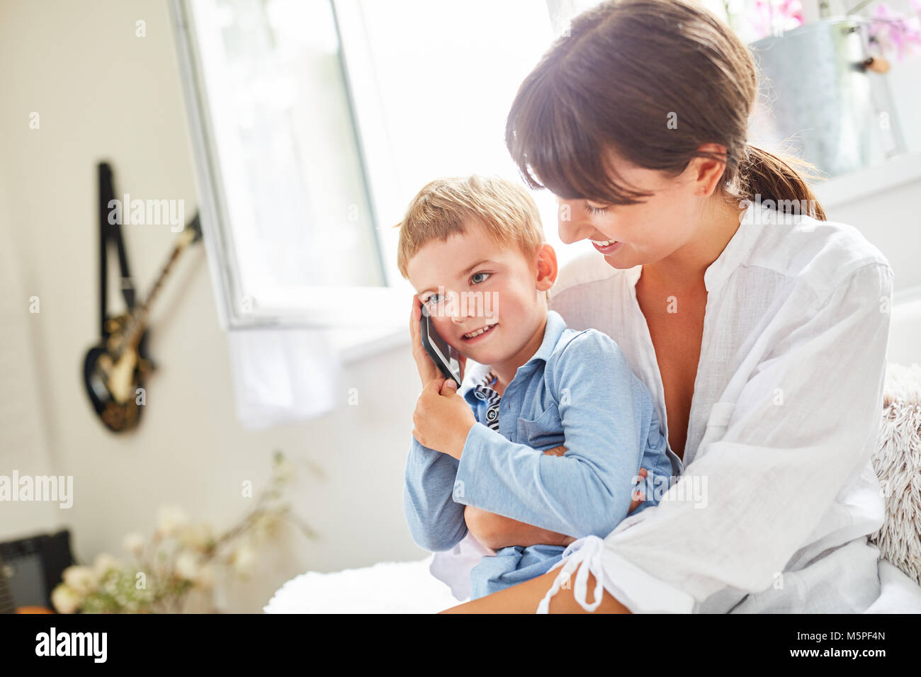 Ragazzo è di telefonare con lo smartphone sulla madre di giro a casa Foto Stock