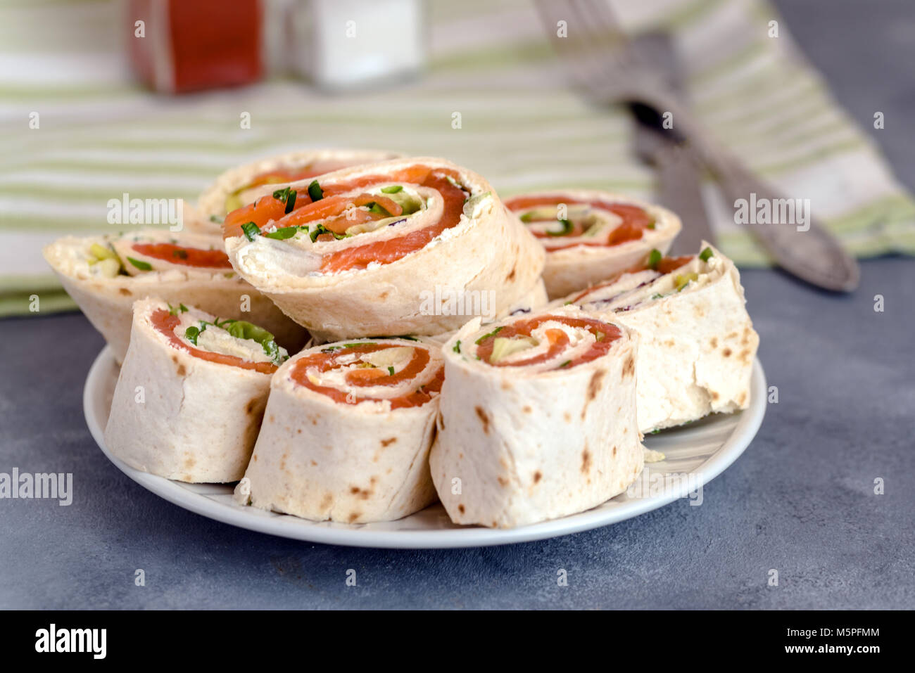 Rotoli di sottili frittelle con salmone affumicato e crema di formaggio, erba cipollina e lattuga. Foto Stock
