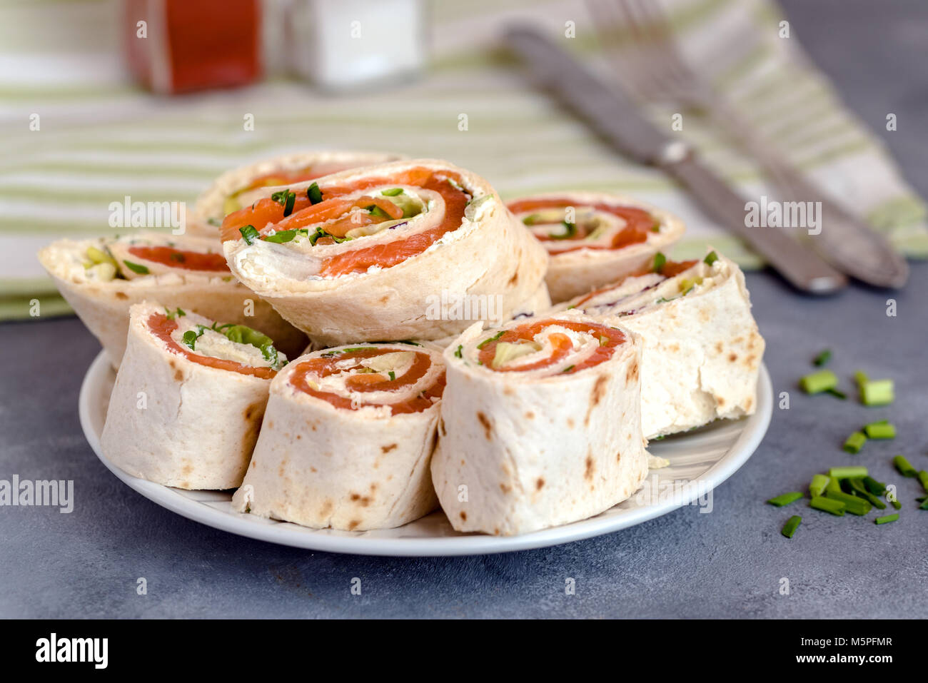 Rotoli di sottili frittelle con salmone affumicato e crema di formaggio, erba cipollina e lattuga. Foto Stock