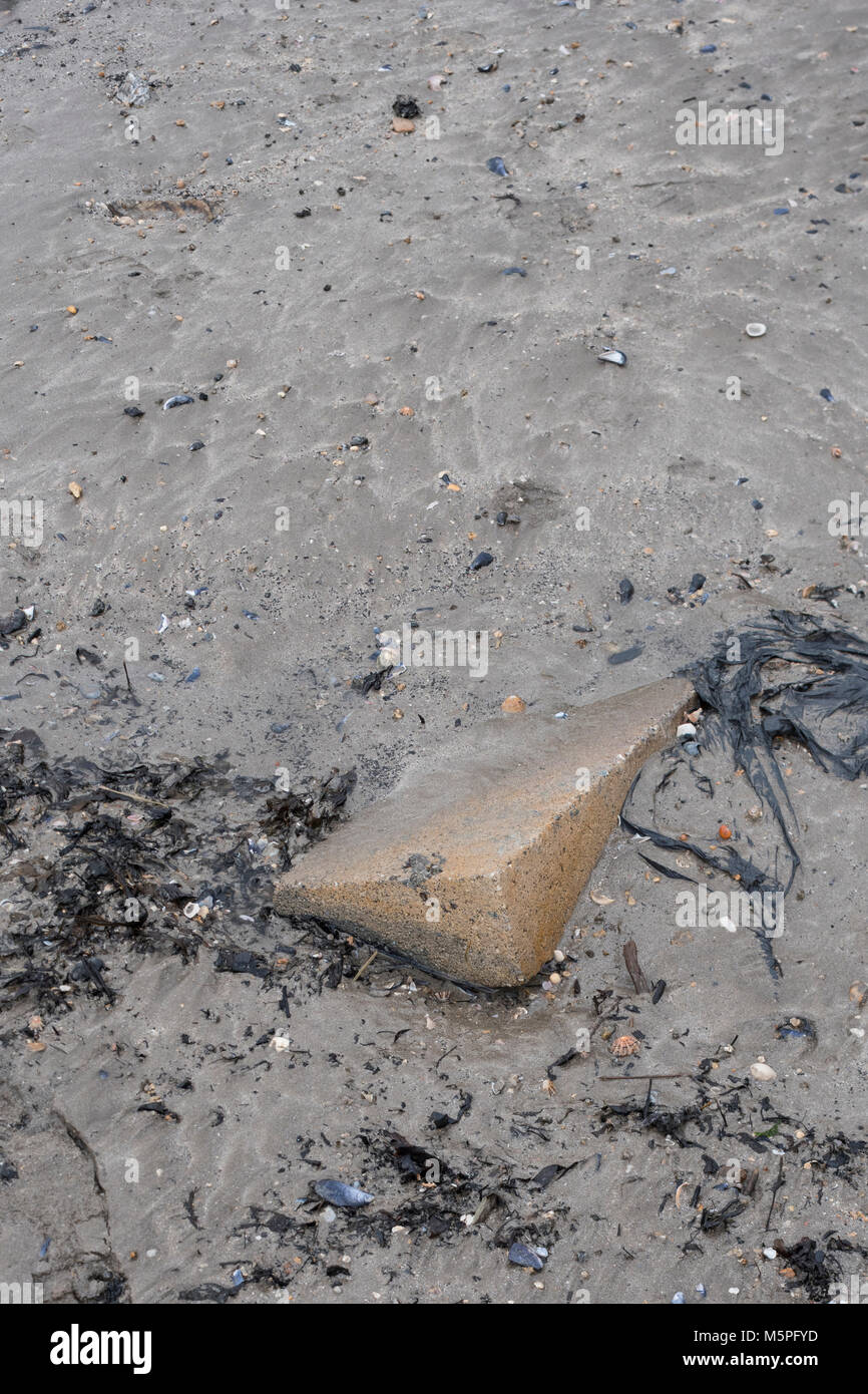 Blocco di calcestruzzo incorporato in umido di sabbia sulla spiaggia - metafora per stick nel fango, prive di immaginazione, andando da nessuna parte veloce, progressi limitati, l'insieme nei vostri modi Foto Stock