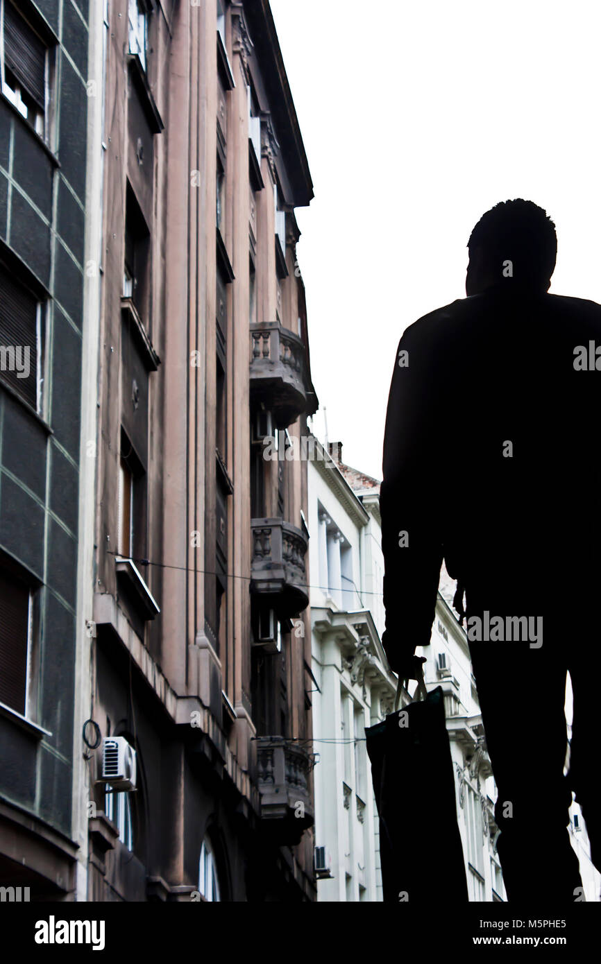 Silhouette di un giovane uomo che cammina e sfocata città architettura , a basso angolo di visione Foto Stock