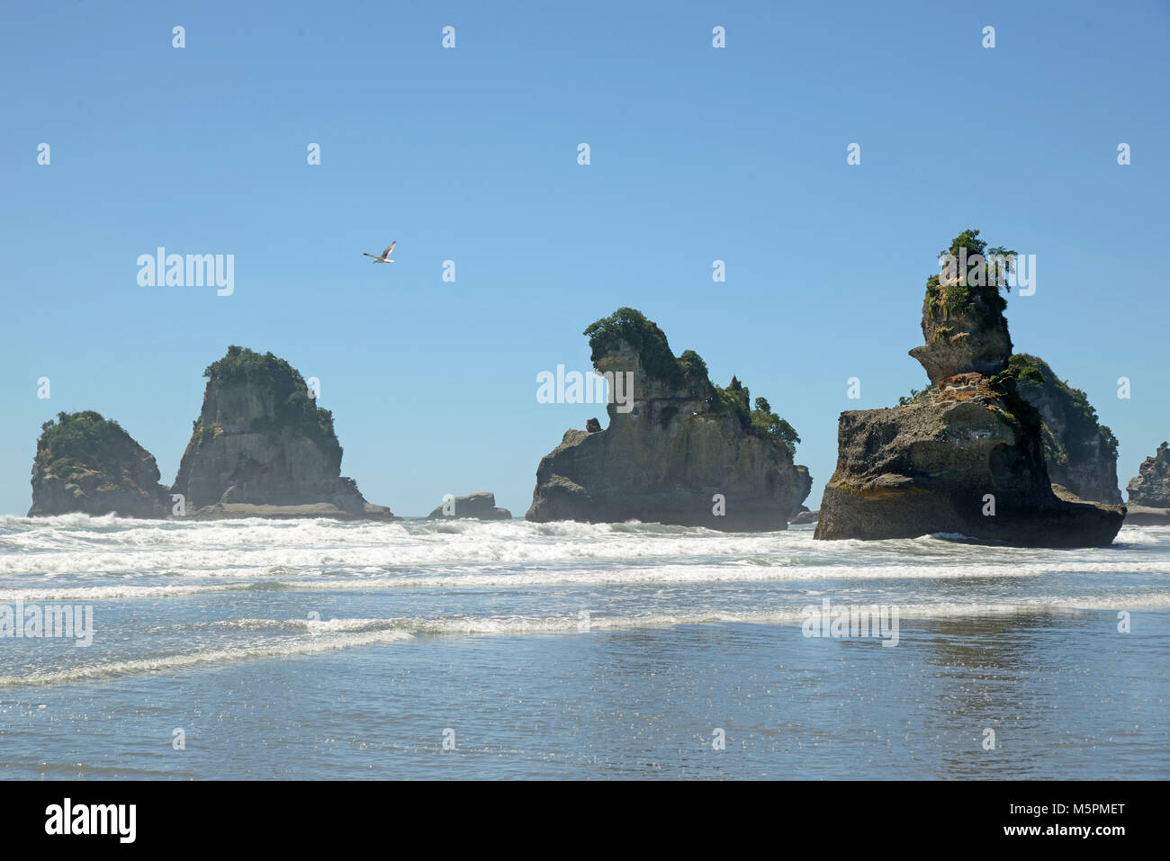 La bassa marea rivela la presenza di un gruppo di piccole isole a West Coast Beach, Isola del Sud, Nuova Zelanda Foto Stock