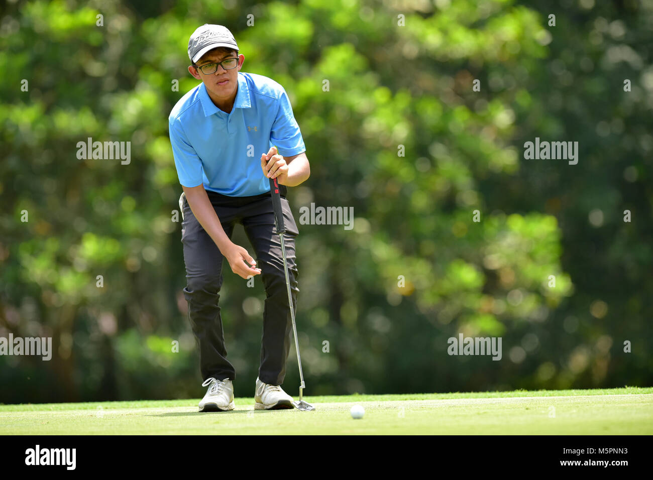 Danau, UKM Bangi - 11 febbraio: Ryan Fernandez linee fino il suo putt sul terzo verde durante la finale di sound del Danau junior campionato a Danau Golf Club Foto Stock