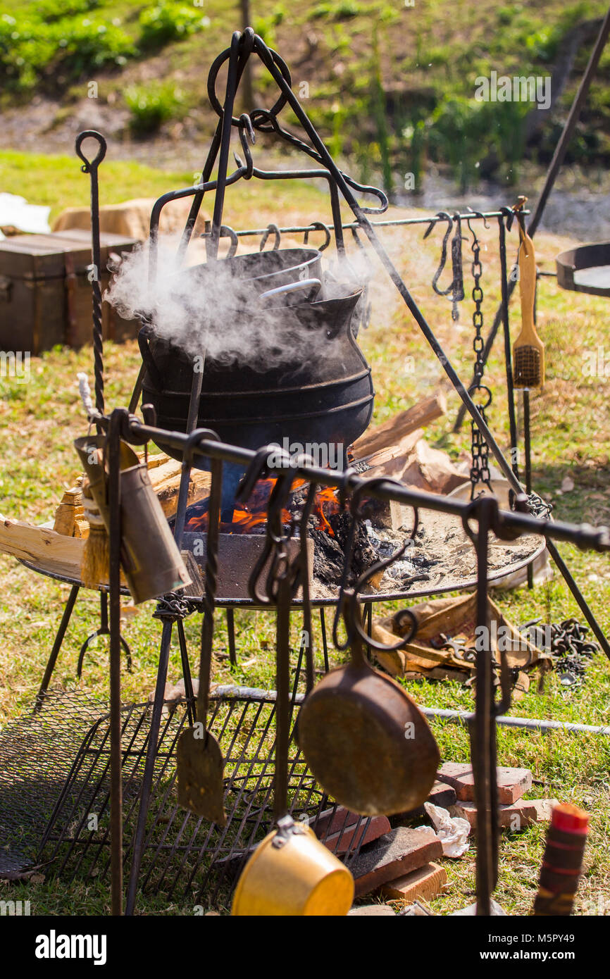 Cucina outdoor in una ghisa pentola su un di legno aperto il fuoco in un accampamento durante una rivoluzione americana rievocazione storica Foto Stock