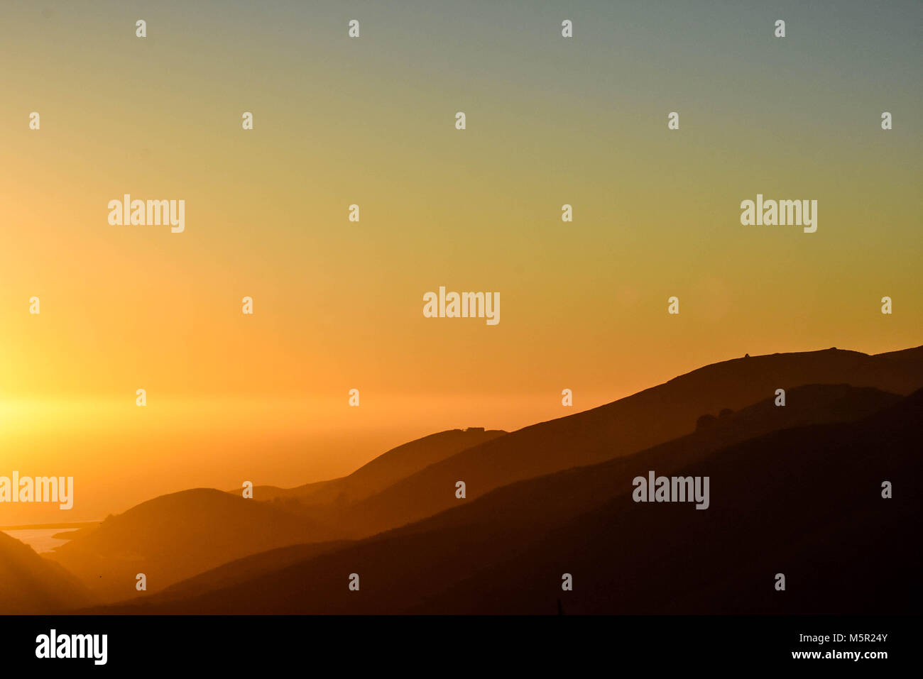 Il tramonto sulle Marin Headlands proietta un bagliore arancione all'orizzonte. Foto Stock
