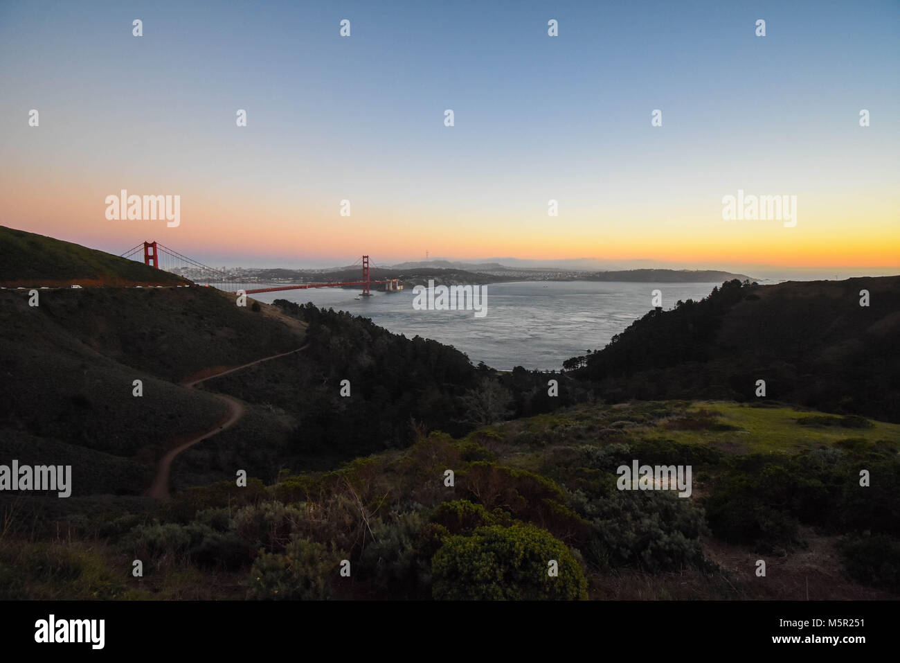 Il sole al tramonto proietta un bagliore sognante su San Francisco e il Golden Gate. Foto Stock