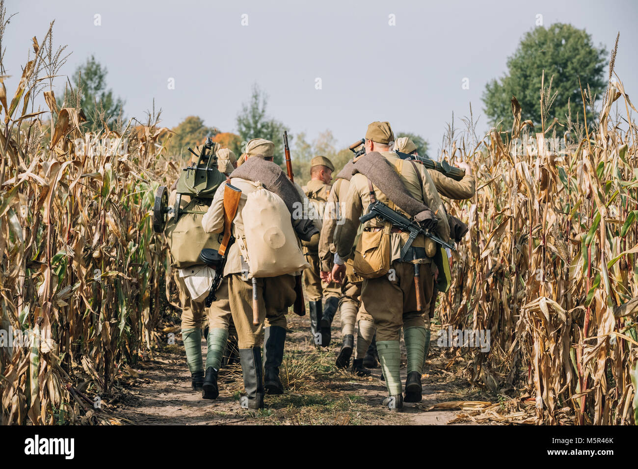 Reenactors Uomini vestiti come Soviet russo Esercito Rosso soldati di fanteria della II Guerra Mondiale Marching in campo con arma machine-gun a Reenactmen storico Foto Stock