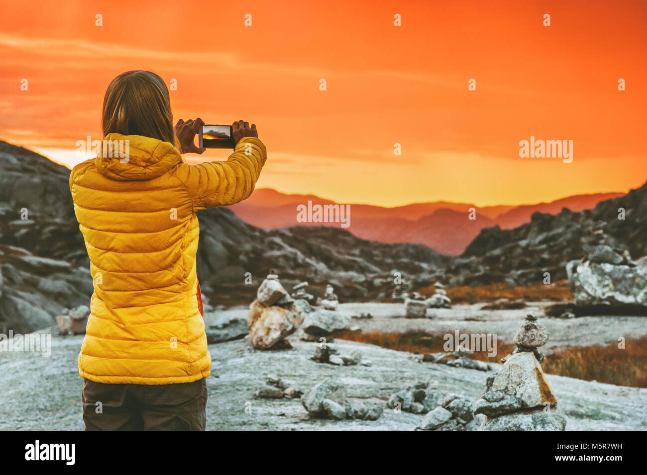 Donna blogger prendendo foto tramite smartphone del tramonto Montagne Paesaggio stile di vita viaggio avventura concetto vacanze in Norvegia outdoor technolog moderno Foto Stock