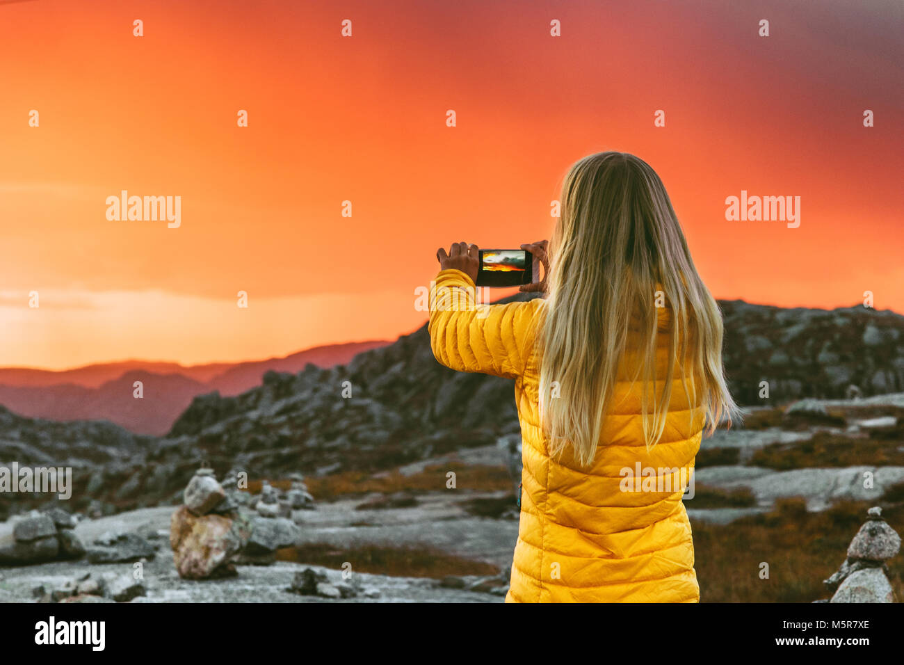 Donna prendendo foto tramite smartphone del tramonto paesaggio delle montagne di viaggio e lo stile di vita moderno concetto di tecnologia avventura vacanze outdoor naturale sky Foto Stock