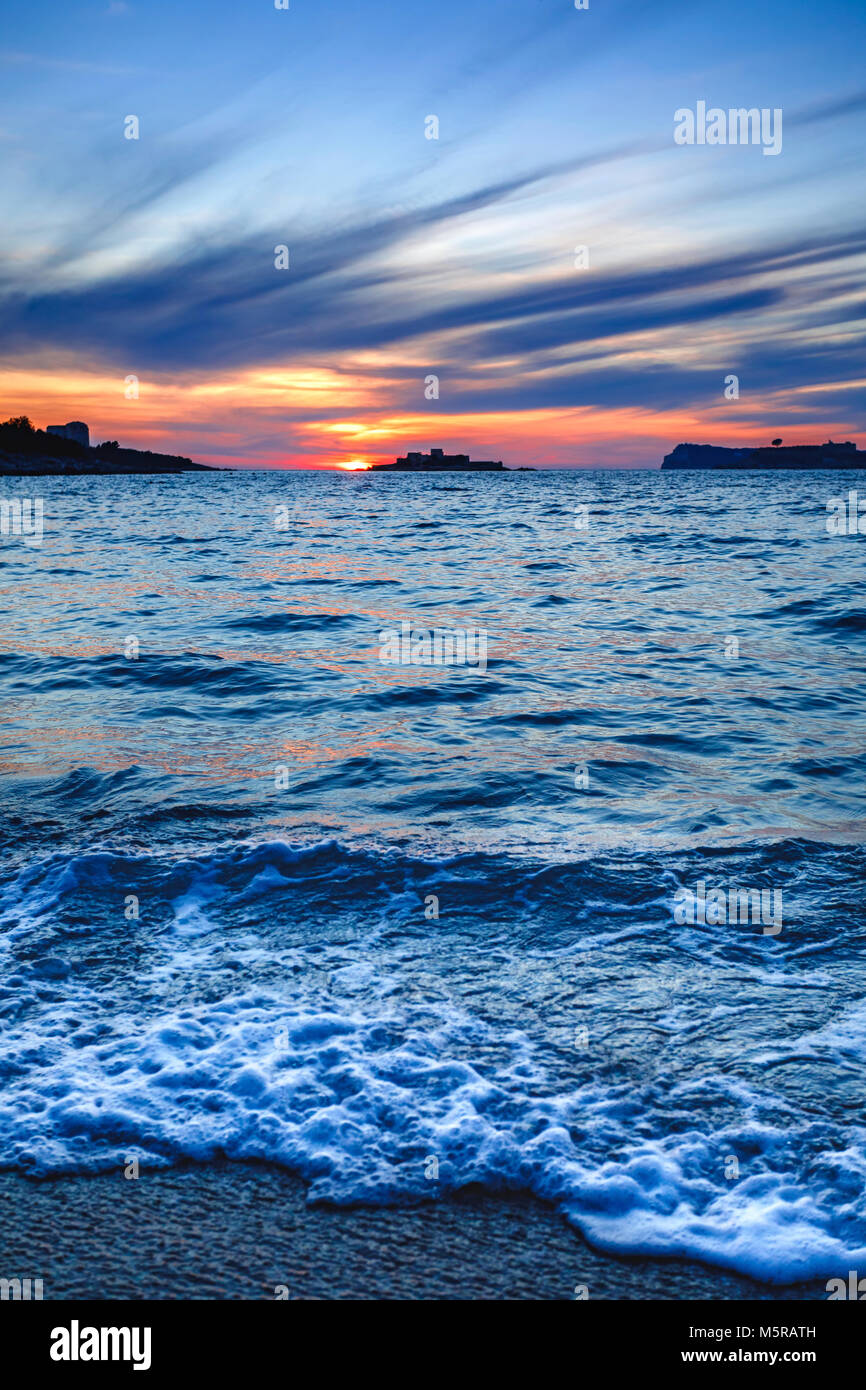 Spiaggia con le onde del mare al tramonto Foto stock - Alamy