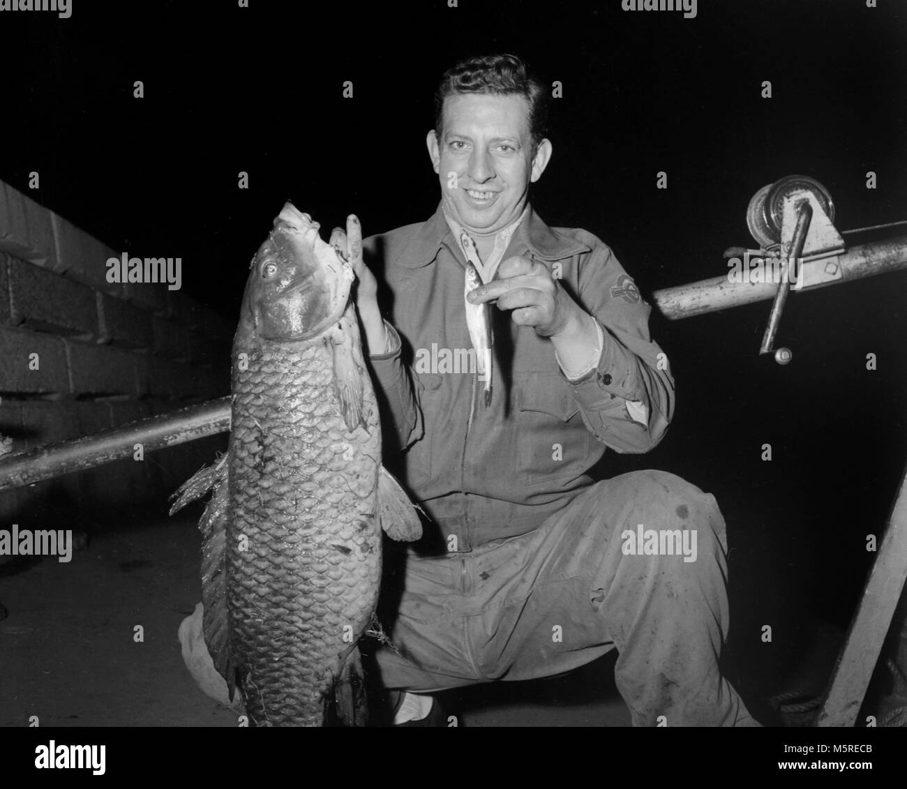 Un uomo è lieta con la grande carpa ha catturato, ca. 1950. Foto Stock