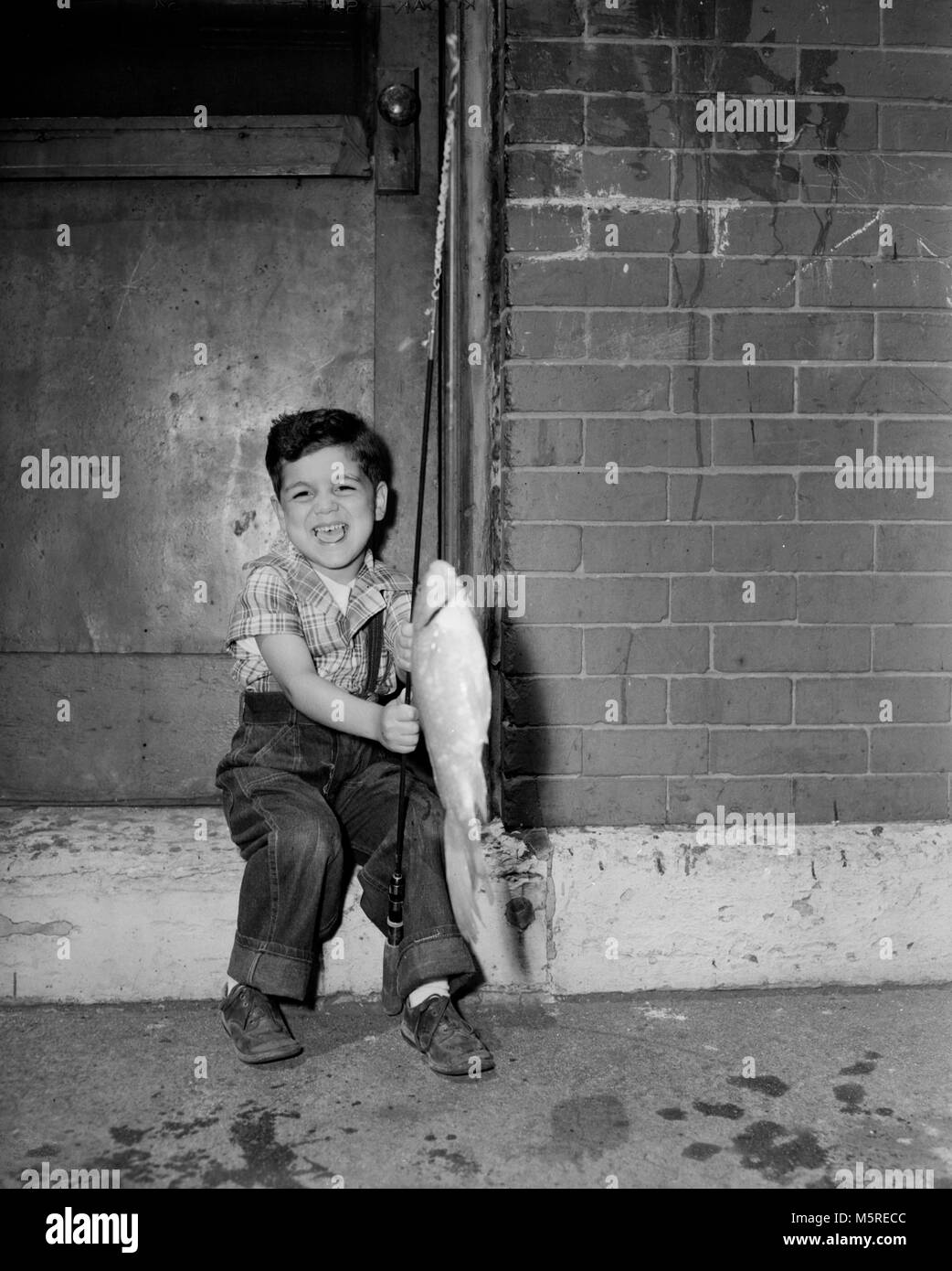 Un ragazzo giovane trattiene un goldfish ha catturato a Chicago, ca. 1950. Foto Stock