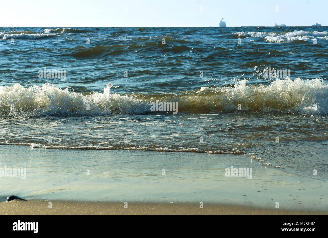 Nave in mare all'orizzonte, una tempesta nel Mar Baltico, onde del mare sulla spiaggia Foto Stock