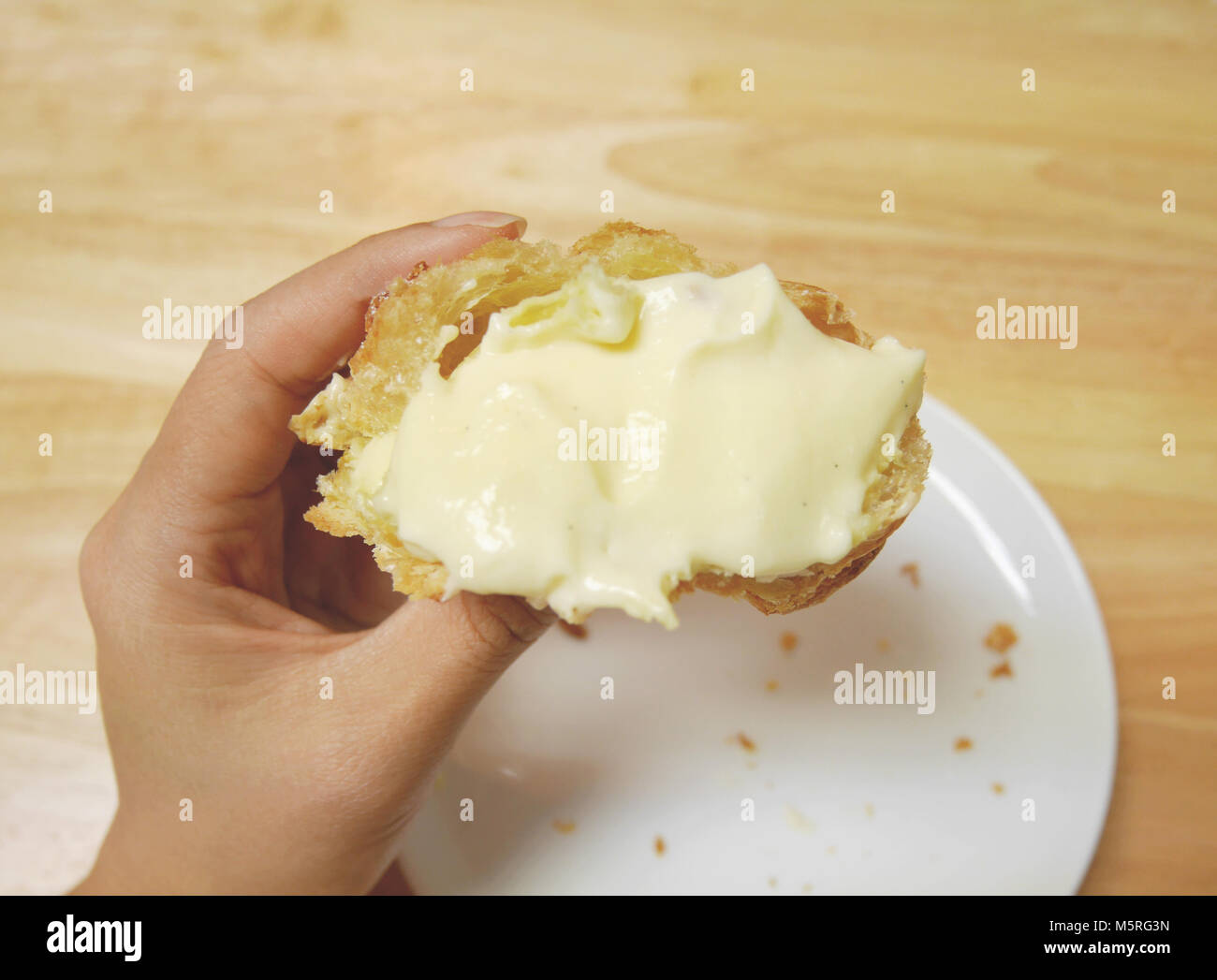 La metà dei fatti in casa giapponese choux soffio di crema, vedendo molti gustosissimi vaniglia riempie l'interno. La panetteria è tenuto su una donna di mano con piastra bianca con Foto Stock