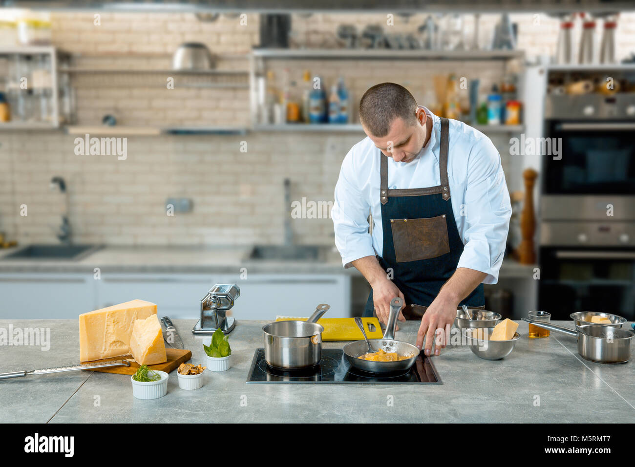 Lo chef friggere il cibo italiano in una padella. Cucina interier Foto Stock