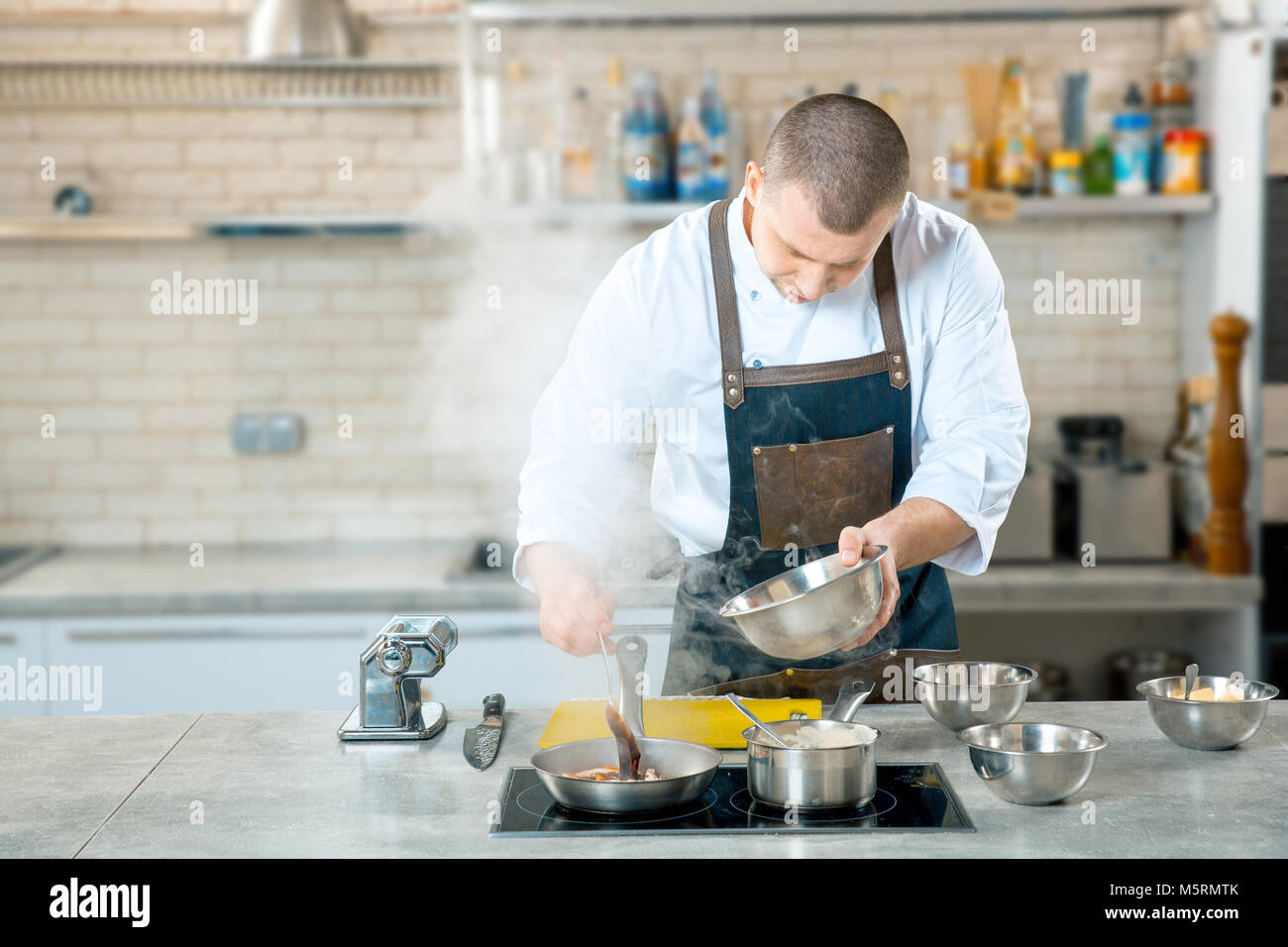 Lo chef friggere il cibo italiano in una padella. Cucina interier Foto Stock