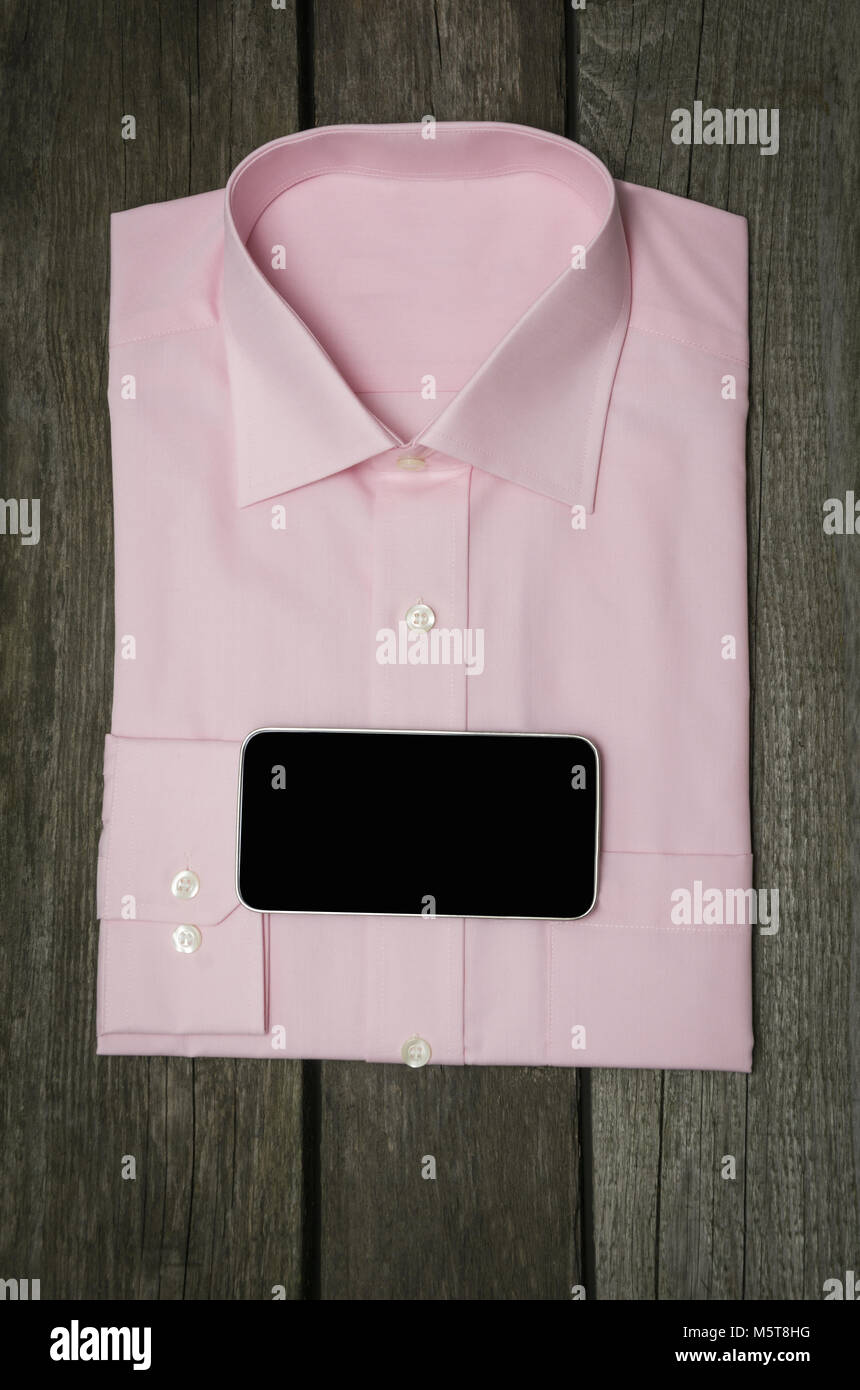 Maglia rosa e mobile sullo sfondo di legno. Vista dall'alto. Foto Stock