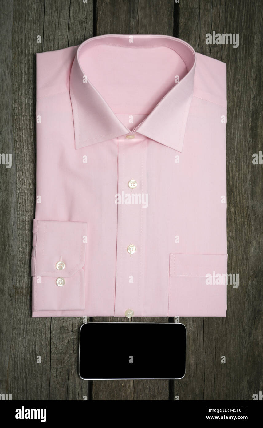 Maglia rosa e mobile sullo sfondo di legno. Vista dall'alto. Foto Stock