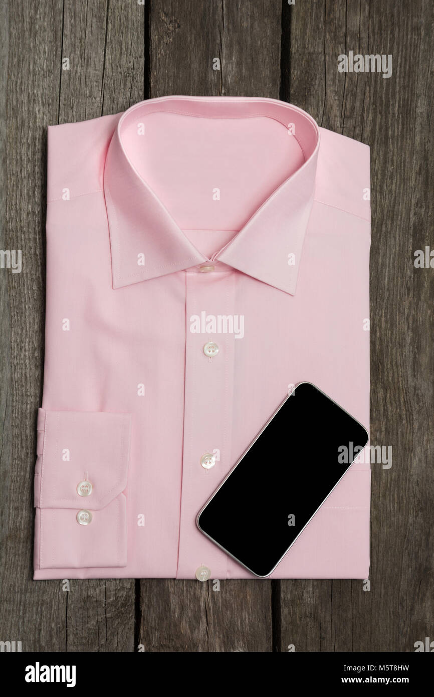 Maglia rosa e mobile sullo sfondo di legno. Vista dall'alto. Foto Stock