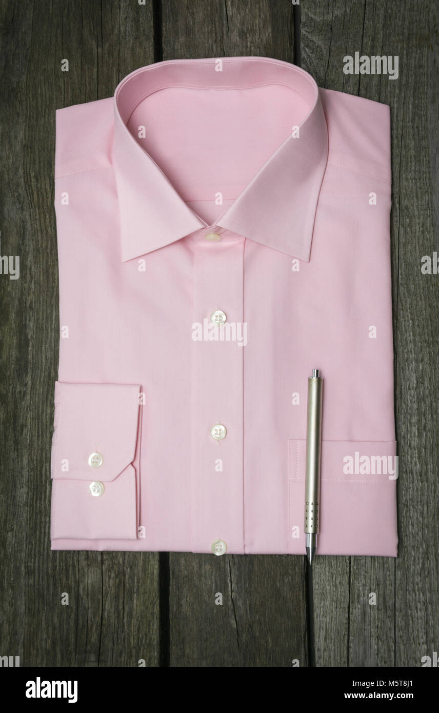 Nuova Maglia rosa e penna su sfondo di legno. Vista dall'alto. Foto Stock
