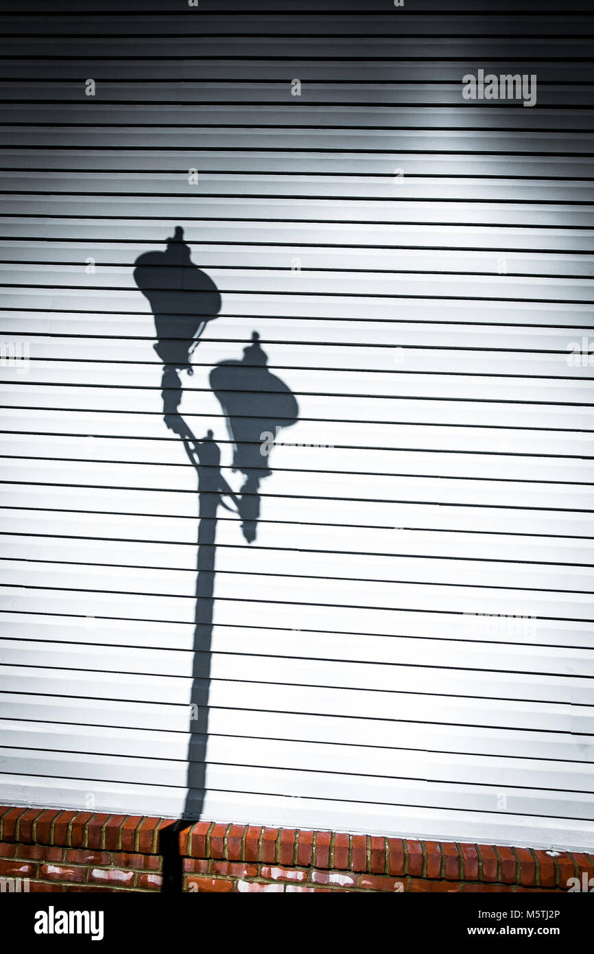 Accoppiata lampione getta un'ombra su vinile sciavero di un edificio la parete. Foto Stock