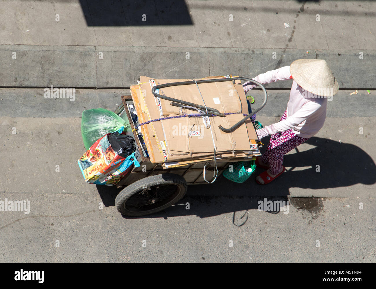 A Saigon, Vietnam, DIC 17 2017, la raccolta di rifiuti riciclabili per le strade della città di Ho Chi Minh. Donna vietnamita spingendo un carrello pieno di borse, Saigon Foto Stock