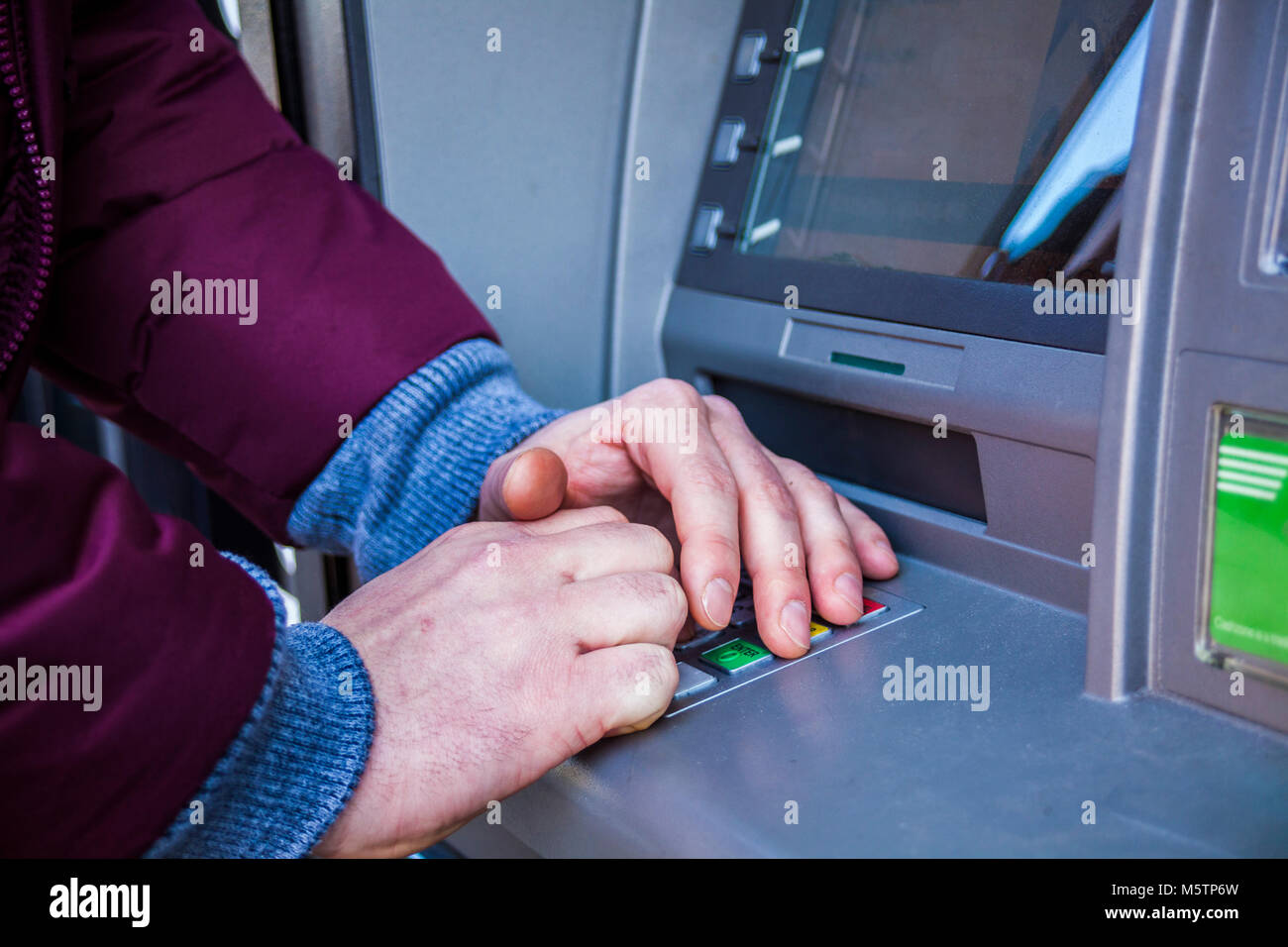 Mani digitando il PIN al bancomat per denaro contante ritiro Foto Stock